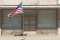 American flag flying outside a building on a main street. - PhotoDune Item for Sale