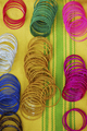 Coloured bangles paid out on a yellow and green striped background. - PhotoDune Item for Sale
