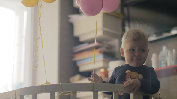 Playful Baby Girl with Balloons in the Crib