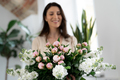 Smiling, happy woman holding a bunch of flowers indoors - PhotoDune Item for Sale