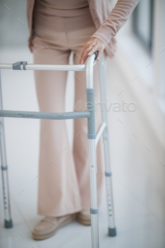 lding a mobility walker while walking down a hallway.