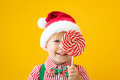 Happy child holding lollipop in hand against yellow background - PhotoDune Item for Sale