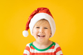 Funny child dressed Santa Claus hat against yellow background - PhotoDune Item for Sale