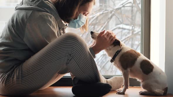 Woman Sitting in Mask at Window with a Dog