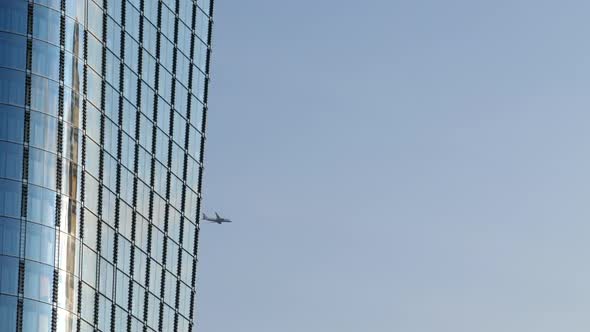 Landscape with side facade of modern building and aircraft flying. Static