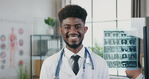 Black-Skinned Medic in white Coat with Stethoscope Standing in front of Camera in Clinic Lab