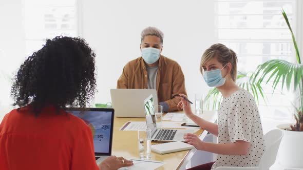 Office colleagues wearing face masks discussing in meeting room at office