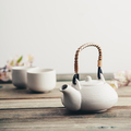 White teapot, cups, sakura flowers on wooden table against the white wall - PhotoDune Item for Sale