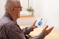 Retired elderly man talking to NHS GP female doctor via virtual telemedicine video call using tablet - PhotoDune Item for Sale