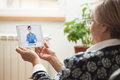 Elderly caucasian woman talking to young female e-doctor via online video chat - PhotoDune Item for Sale