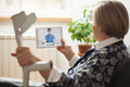 Retired woman holding crutch and tablet computer talking to orthopedic female doctor via video call - PhotoDune Item for Sale