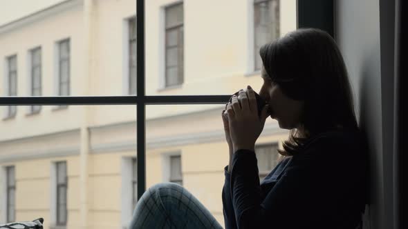 Woman Drinking Tea and Resting on Windowsill