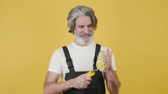 Worker Holding Paint Brush and Smiling on Yellow Background