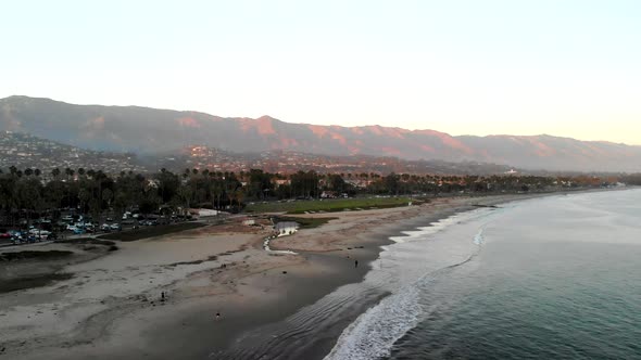 Aerial drone shot at sunset above a Pacific Ocean beach and marina looking over the the beautiful ci