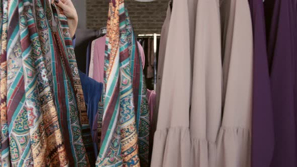 A Young Muslim Woman Choosing Clothes at the Store