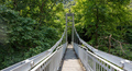 Narrow suspension bridge over Pineios River. Greece, Tempi Vale, Thessaly. Tree foliage background - PhotoDune Item for Sale