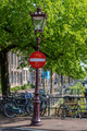 Stop sign in Amsterdam Netherlands Holland. Bike parked on a canal bridge, traditional houses - PhotoDune Item for Sale