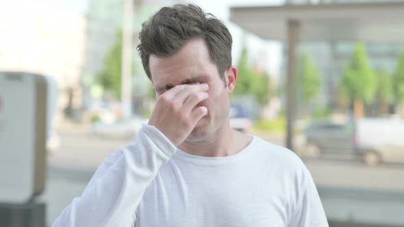 Portrait of Tired Young Man Rubbing Eyes Outdoor