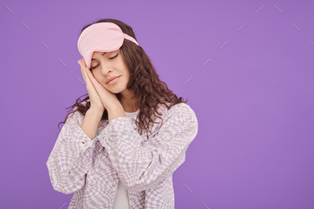 with closed eyes pretending to sleep on purple background