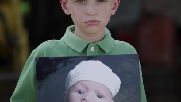 Slow motion from photo to boys face of him showing photo with cleft palate.