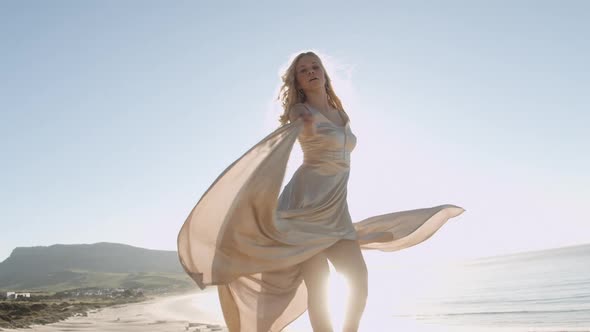 Dancing Blond Woman In Gold On Sunlit Beach