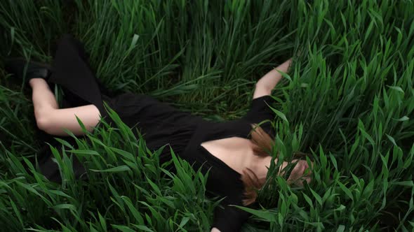 Girl In Black Dress Lies In The Grass.