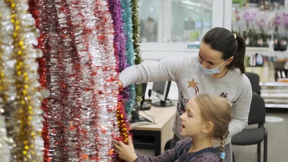 Child Girl with Mother Choosing Xmas Decorations