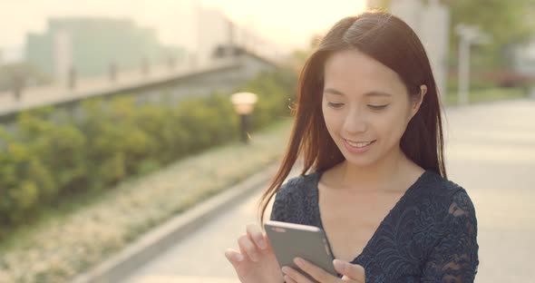 Woman use of mobile phone under sun flare