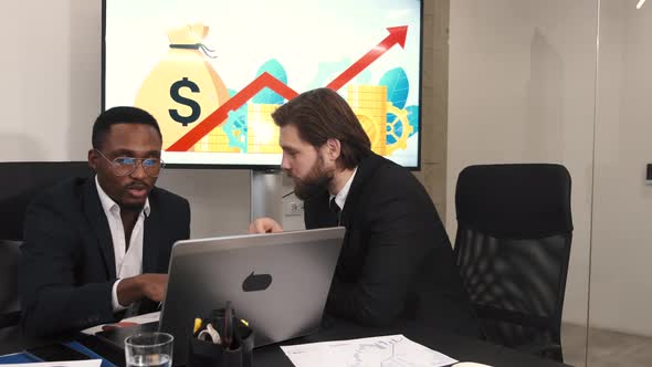 Two Businessmen in Suits Having a Discussion at Office