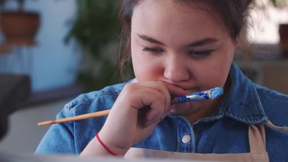 A Chubby Indpired Woman Paint Artist Drawing a Painting with a Brush Covered in Oil Paint