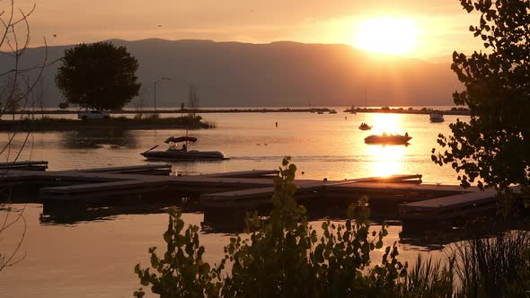 People pulling their boats into the harbor on Utah Lake at sunset