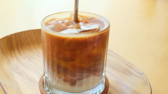 Iced coffee stir in glass on table in cafe.