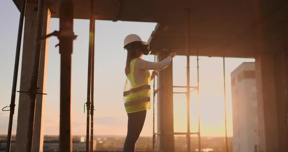 A Woman Engineer at a Construction Site in Virtual Reality Glasses Moves Her Hands Simulating the