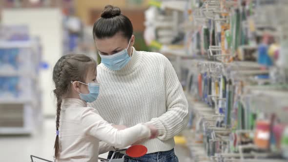 Mother and Child Wearing Protective Masks Choose Stationery at the Supermarket