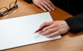 Female left hand with a pen on a blank paper, close up, wooden office table. Write, sign concept - PhotoDune Item for Sale