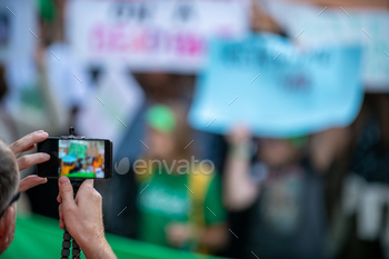  Holding Phone and Recording Protest.