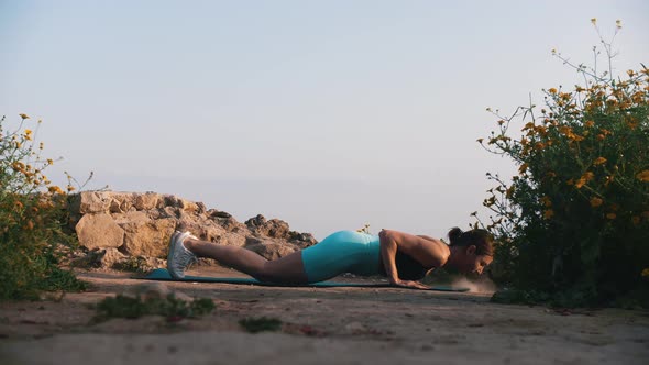 A Woman in Sportswear Doing Fitness Exercises on the Yoga Mat on a Hill