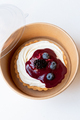Cheesecake tart with berry jam and blueberries on paper food container. Delivery concept.  - PhotoDune Item for Sale