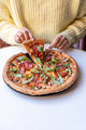 Woman is taking a slice of a salami pizza with mushrooms and arugula leaves.  - PhotoDune Item for Sale