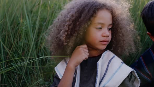 A Girl and a Boy are Chewing Bread While Sitting in a Field of Ears