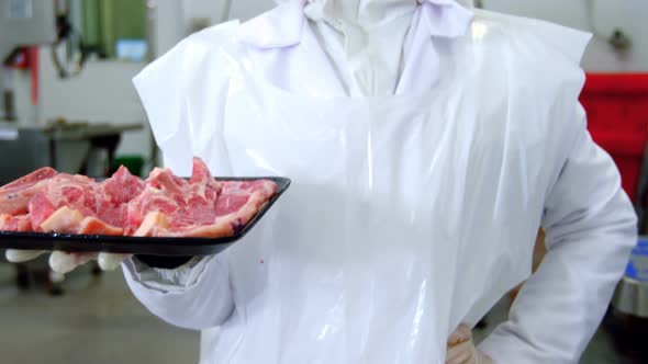 Female butcher holding a tray of raw meat