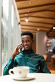 Portrait of handsome young black man in coffee shop using phone - PhotoDune Item for Sale