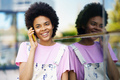 Cheerful black woman talking on smartphone near building - PhotoDune Item for Sale