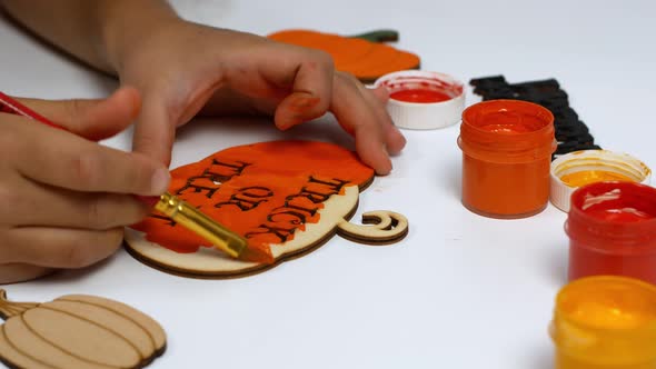 Children make their own Halloween decor. Children paint a pumpkin orange with the inscription