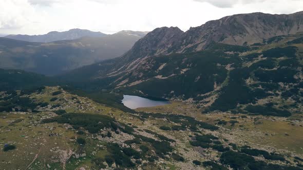 Flying through a valley revealing a lake in the distance.