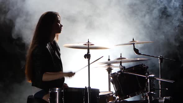 Specially Trained Girl Plays the Drums. Black Smoke Background. Silhouette