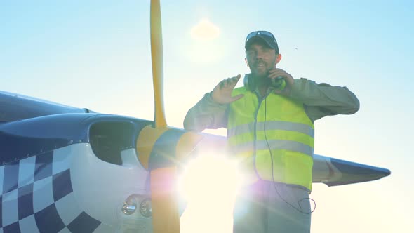 Male Pilot Stands Near a Light Private Airplane. A Person Stands Near a Small Plane