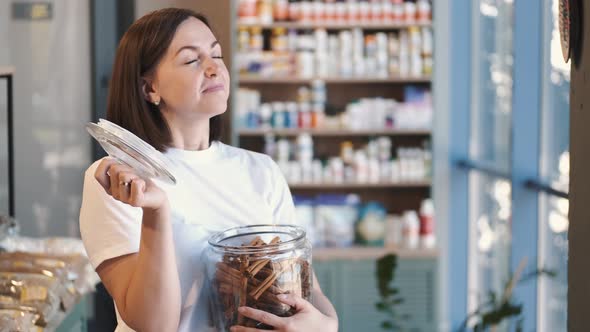 Woman with a Glass Jar of Cinnamon Sticks at the Store