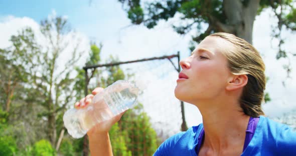 Woman drinking water from bottle during obstacle course 4k