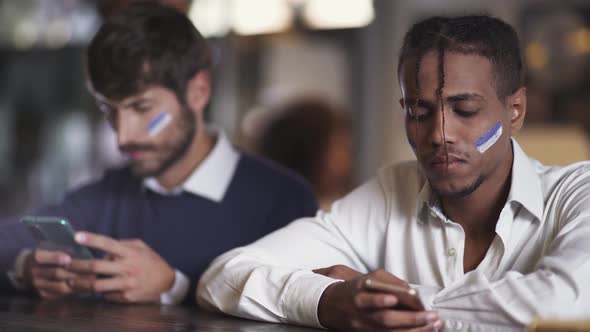 Sports Betting Football Fans Sits in a Bar During a Football Match and Using Their Smartphone